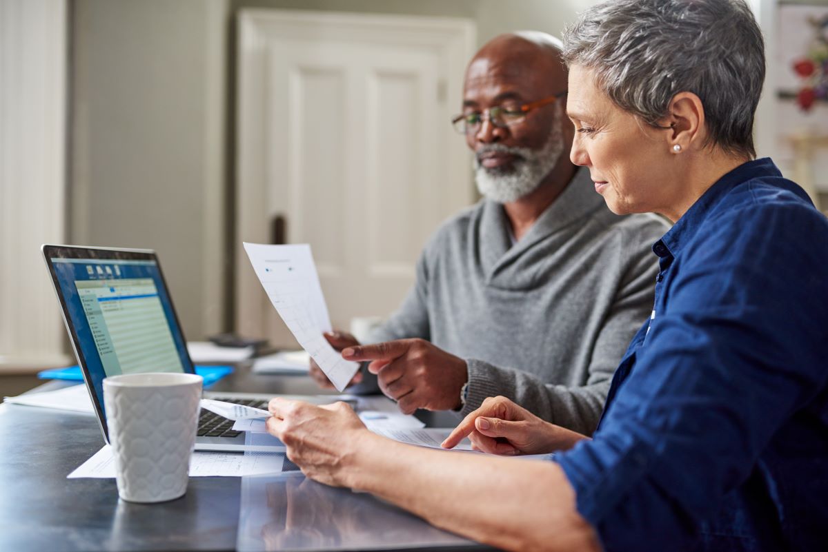 Diverse senior couple looking through documents sitting at a table 