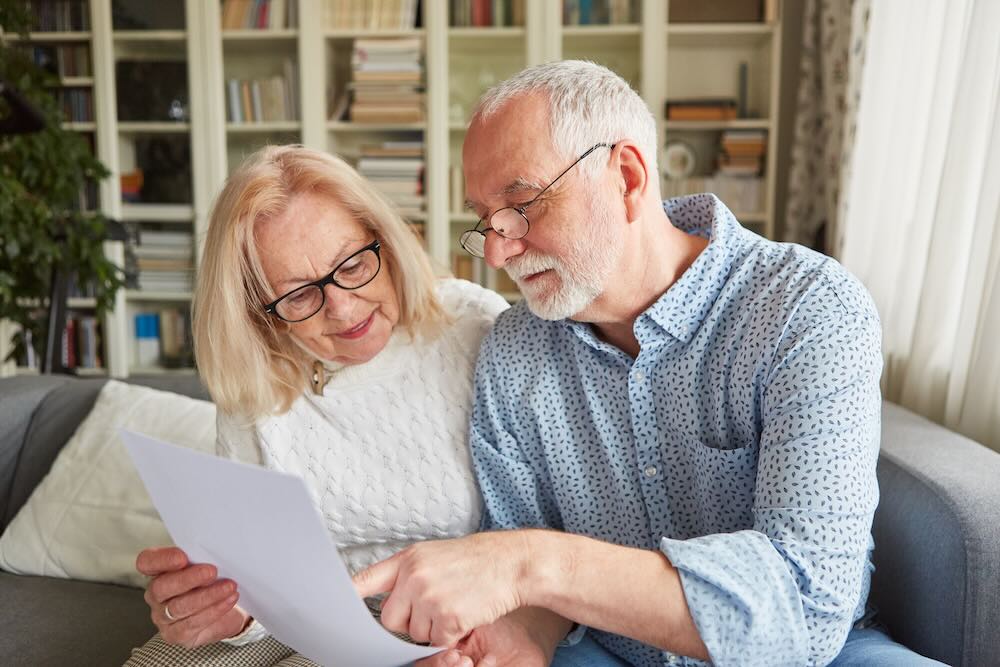 Senior couple looking through documents sitting at their living room